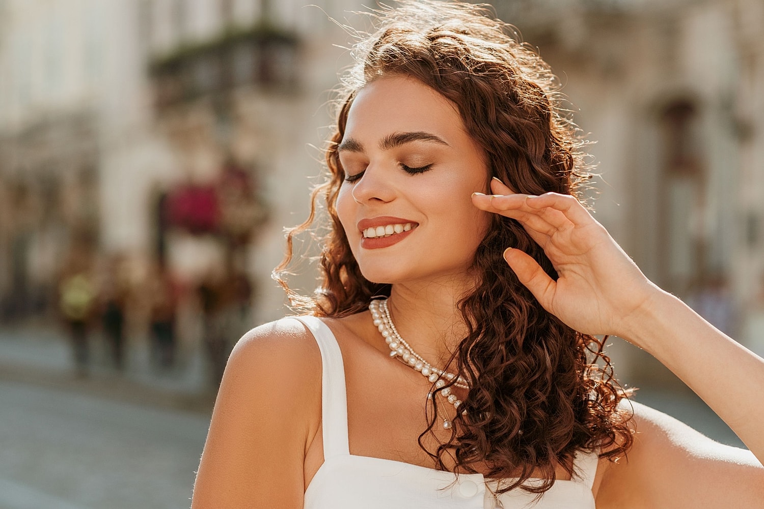 Smiling woman with curly hair in sunlight.