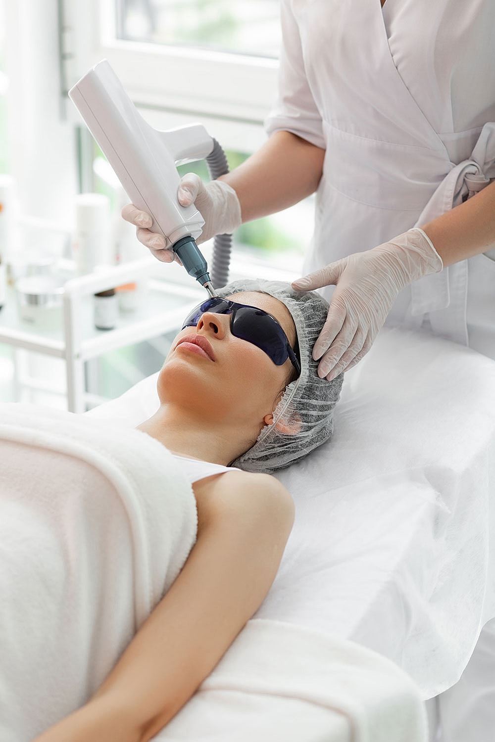 Woman receiving facial treatment with laser equipment.