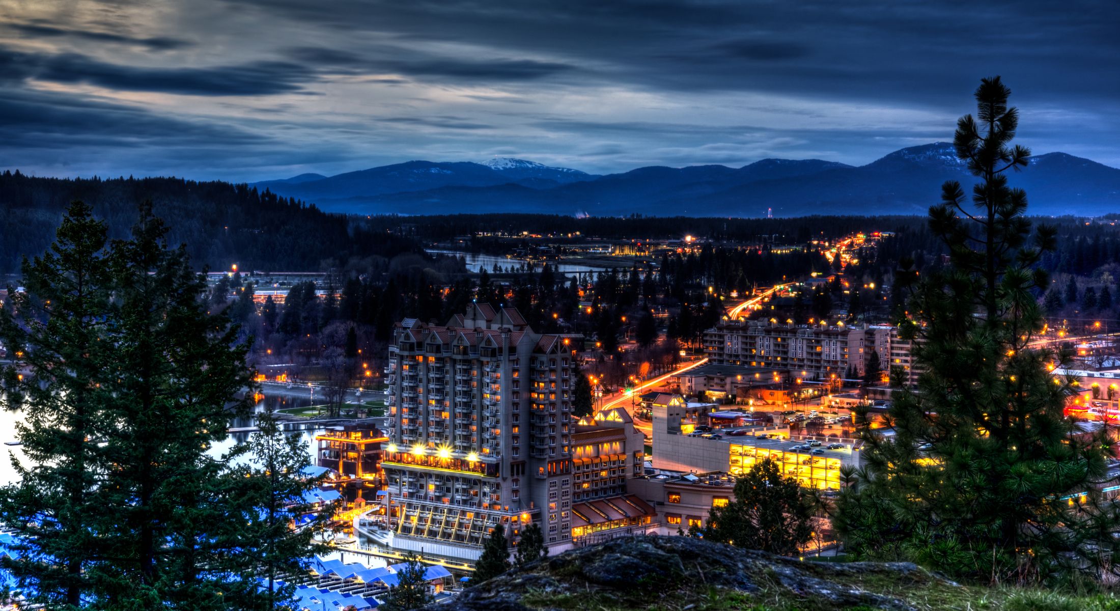 City skyline illuminated at night with mountains.